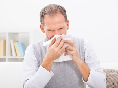 Man sneezing into tissue.