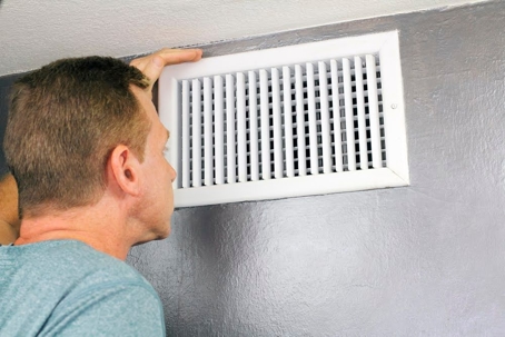 Man looking into vent.